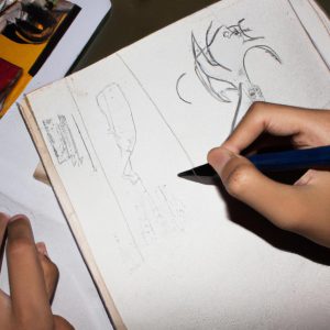 Person writing and drawing comics